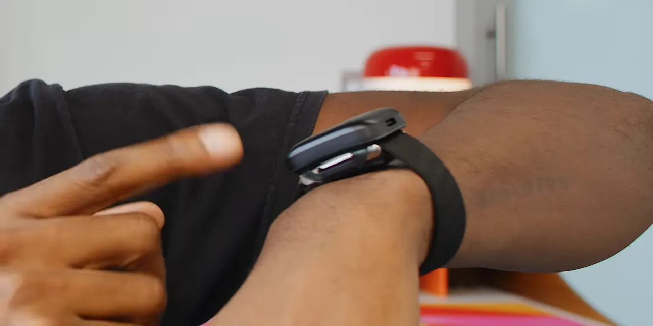 Whoop worn on a wrist with its charging puck attached above the tracker