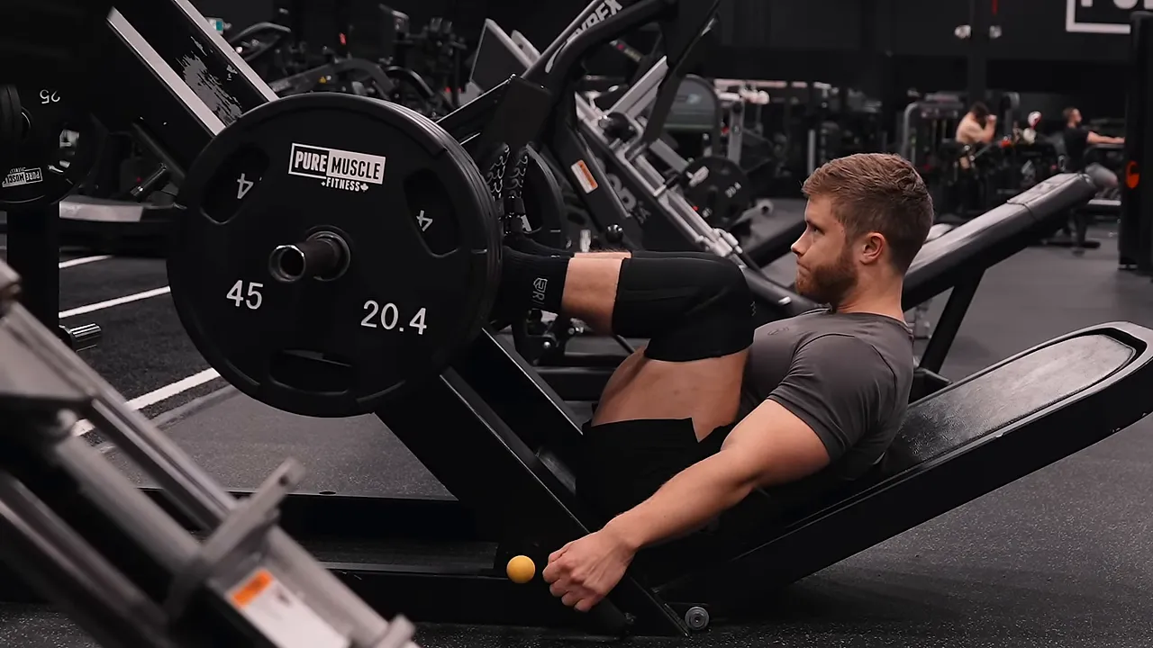 Side view of the bottom position of a leg press with deeply bent knees