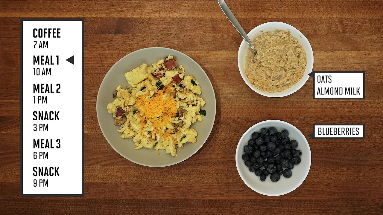 Overhead view of scrambled eggs, a bowl of oats with almond milk, and blueberries on a wooden countertop