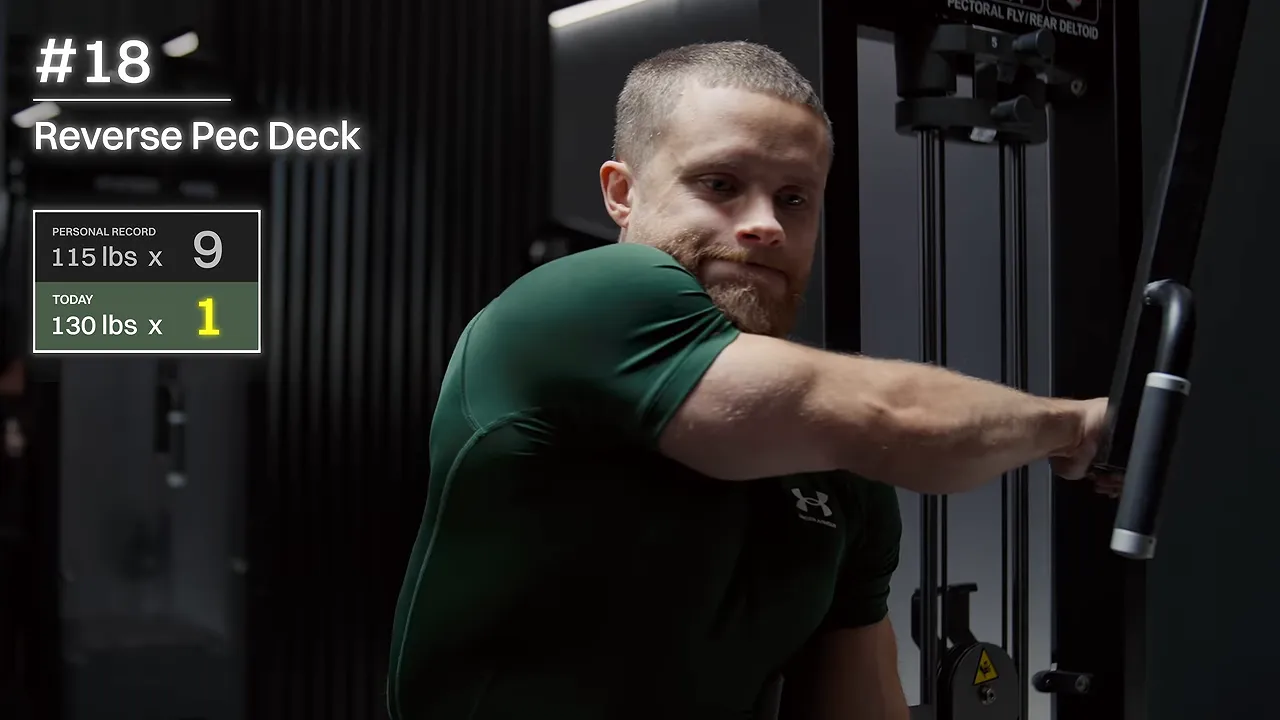 Lifter seated sideways at a reverse pec deck with one arm reaching across his body