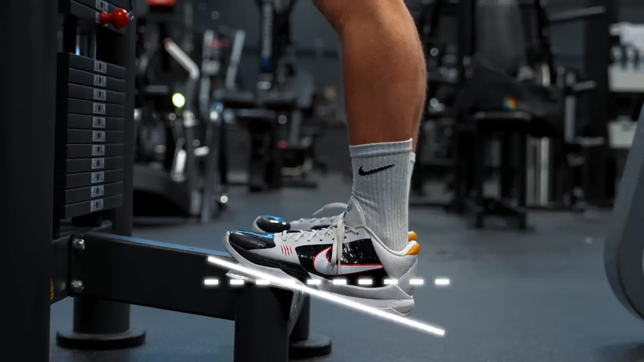 Close-up of a standing calf raise with the heel lowered below the platform and an ankle-angle overlay