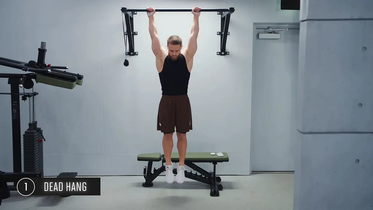 Full-body dead hang from a pull-up bar with straight legs and feet together