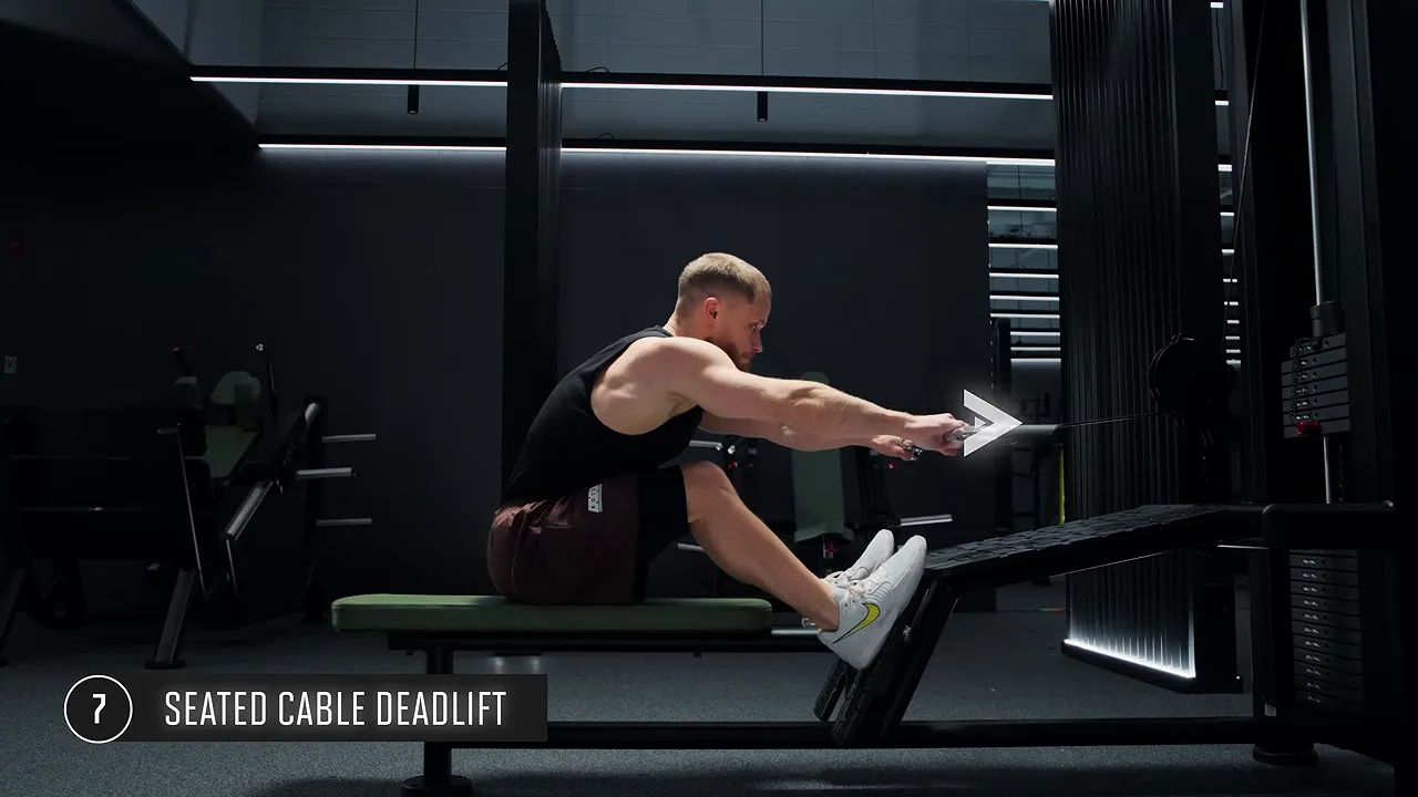 Side view of a seated cable deadlift in the forward hinge position with arms straight and feet on the platform