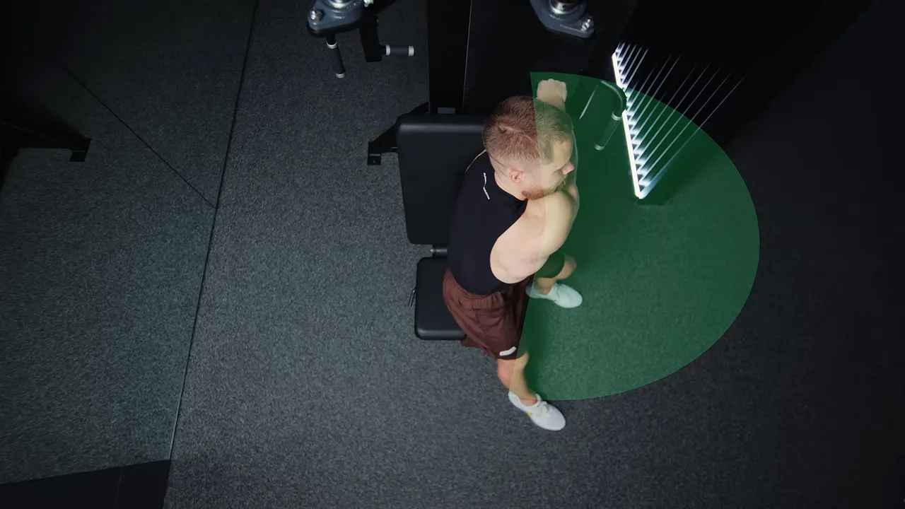 Overhead view of a side-facing single-arm pec deck fly with a green arc marking the arm path
