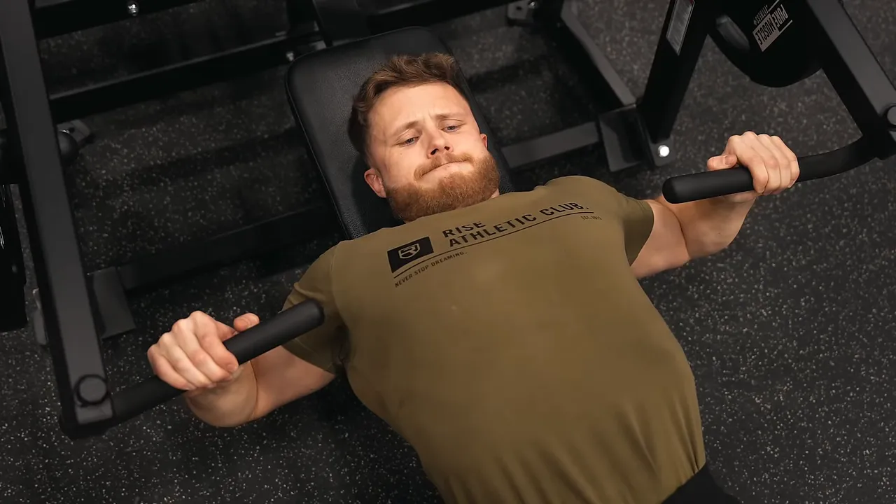 Lifter holding chest press machine handles beside his chest at the bottom position