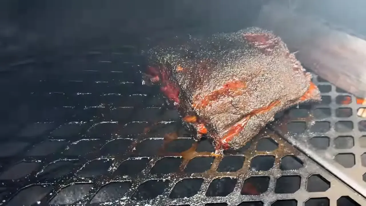 Beef rib rack with dark bark on the expanded-metal grate inside the offset smoker