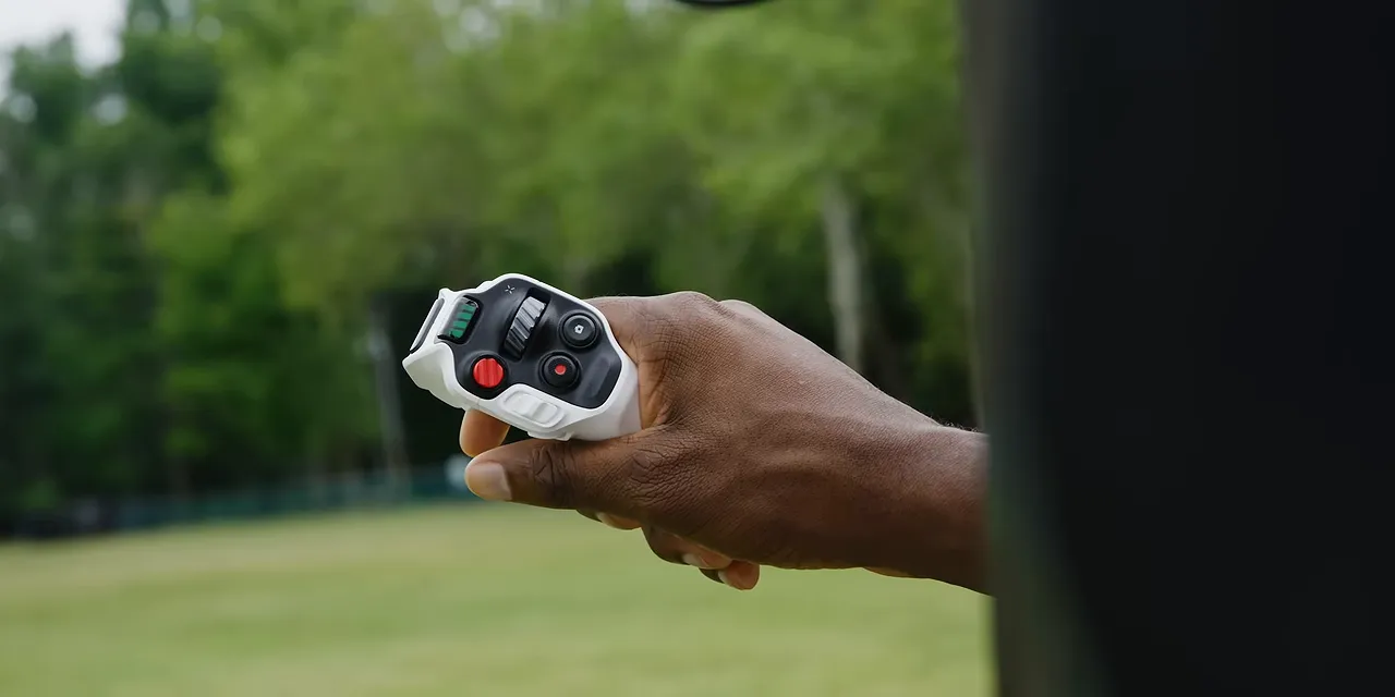 Hand holding the white Antigravity joystick controller with black controls and a red button