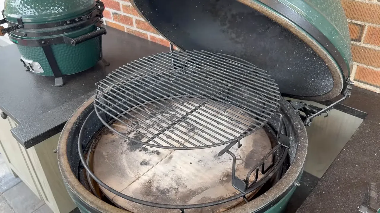 Open Big Green Egg with an elevated cooking rack above ceramic heat deflectors