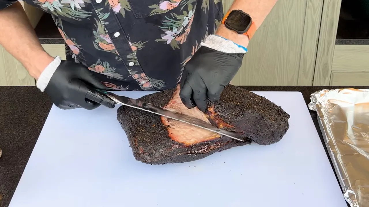 Knife following the exposed seam between the cooked brisket point and flat