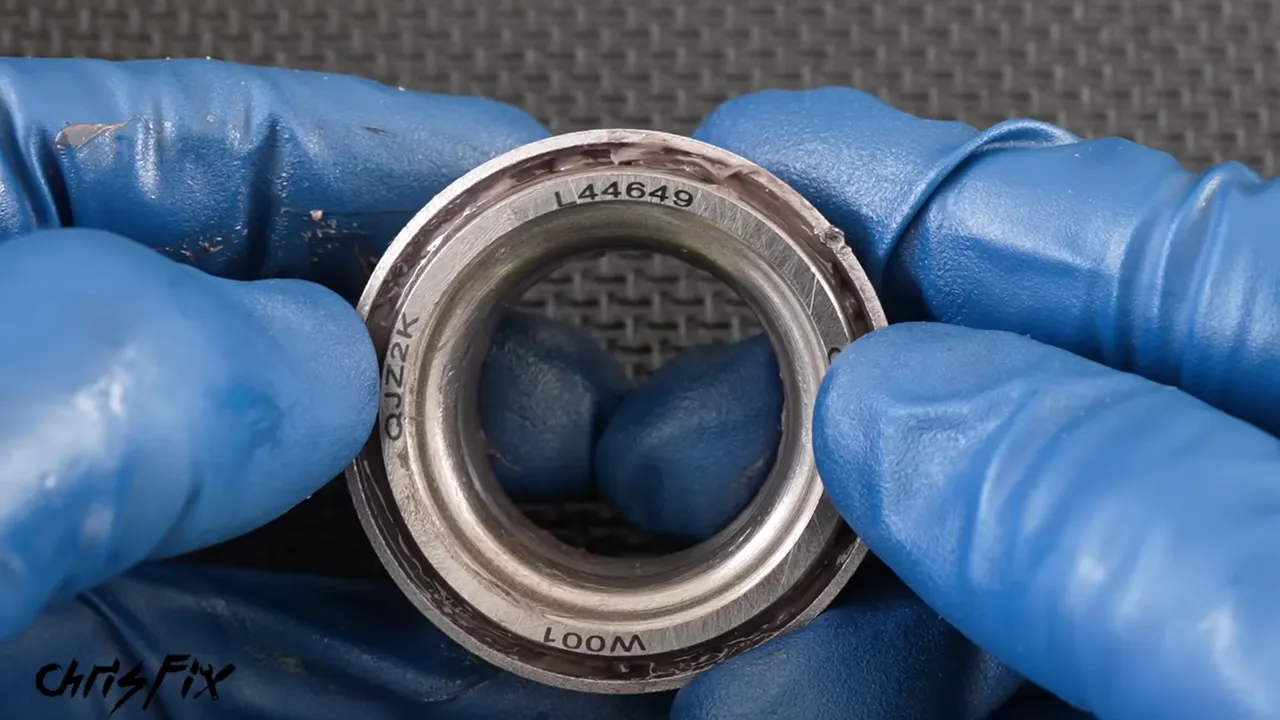 Close-up of a bearing identification marking held between blue gloves