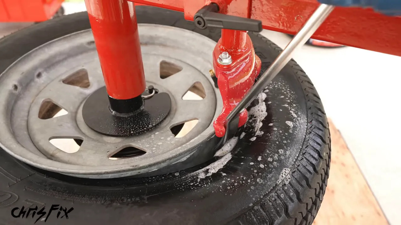 Tire iron lifting a tire bead over the duck head attachment on a manual tire changer