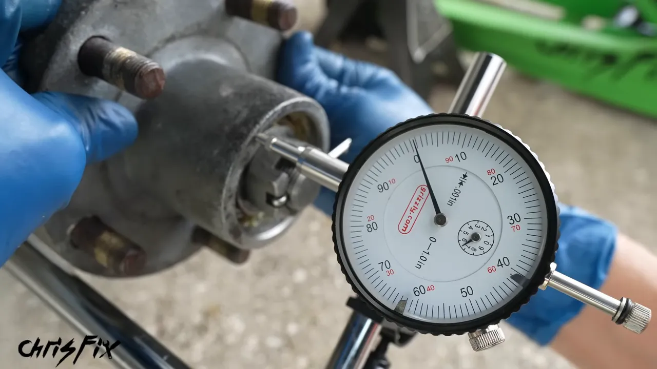 Dial indicator beside a trailer hub while a gloved hand checks hub movement