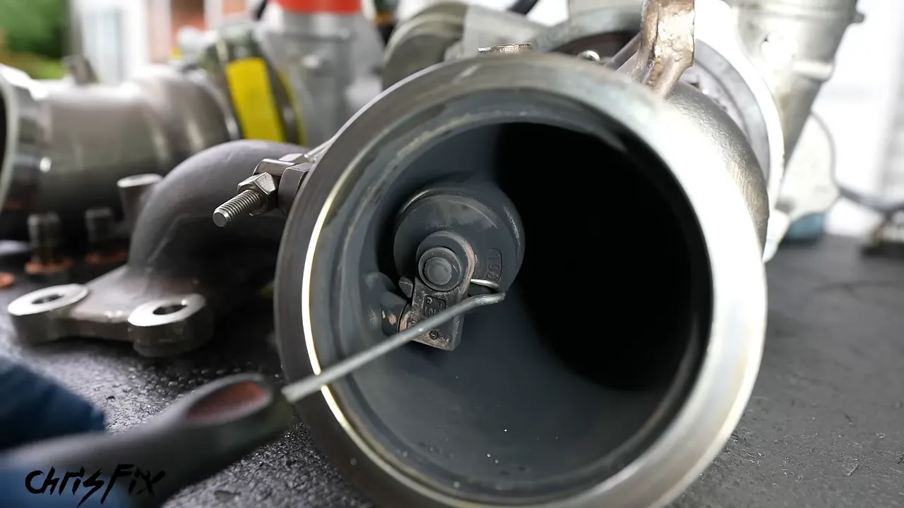 Close-up inside the removed turbocharger showing the wastegate flap and housing