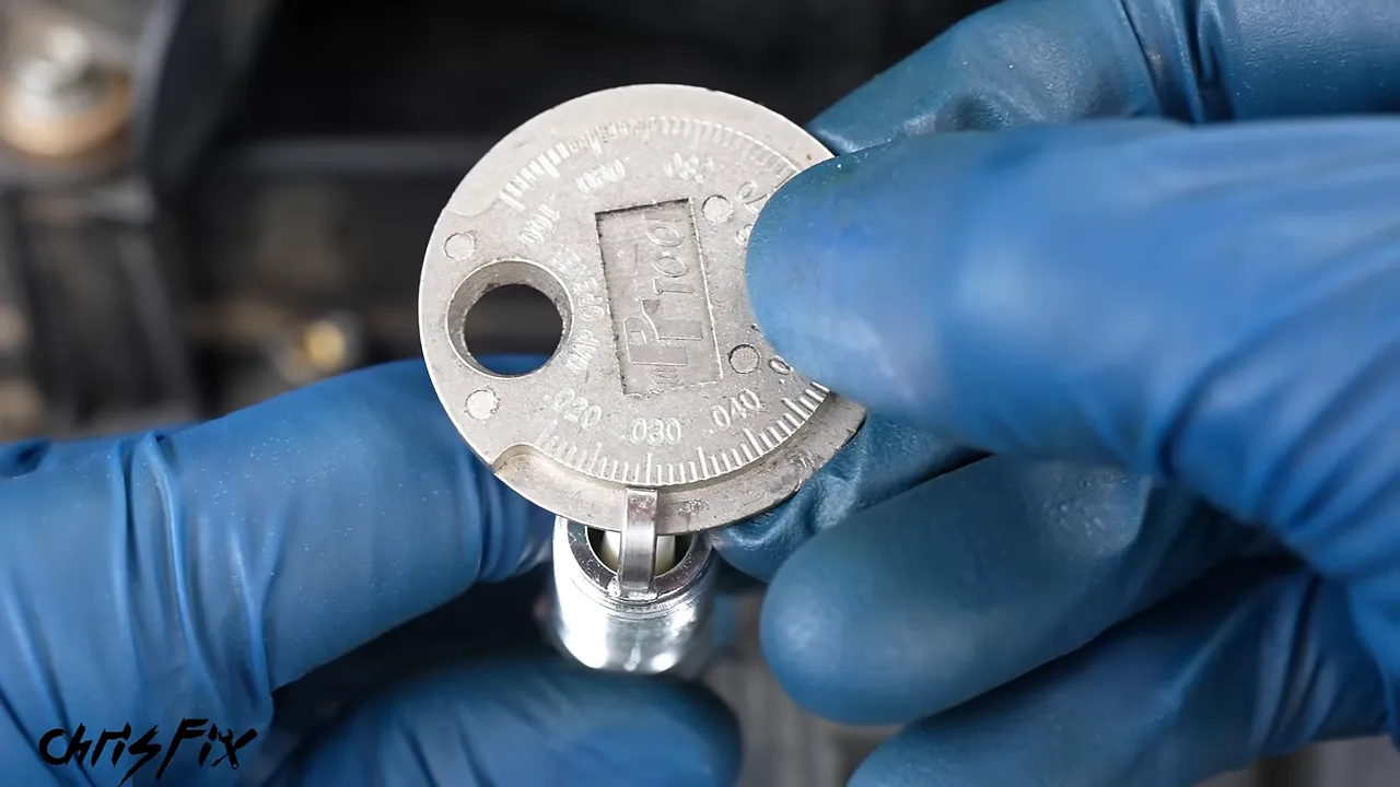 Spark plug held against a round gap gauge near the 0.030-inch marking