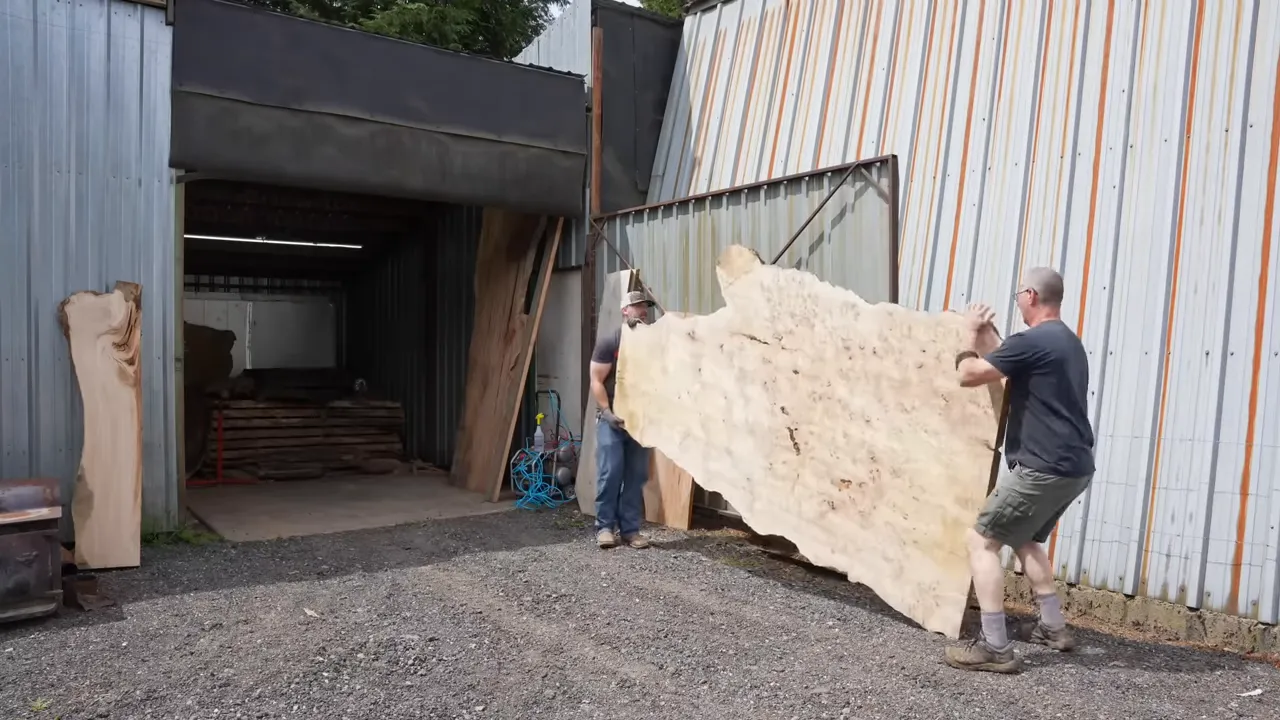 Two people standing beside a large upright pale burl slab outside a shop