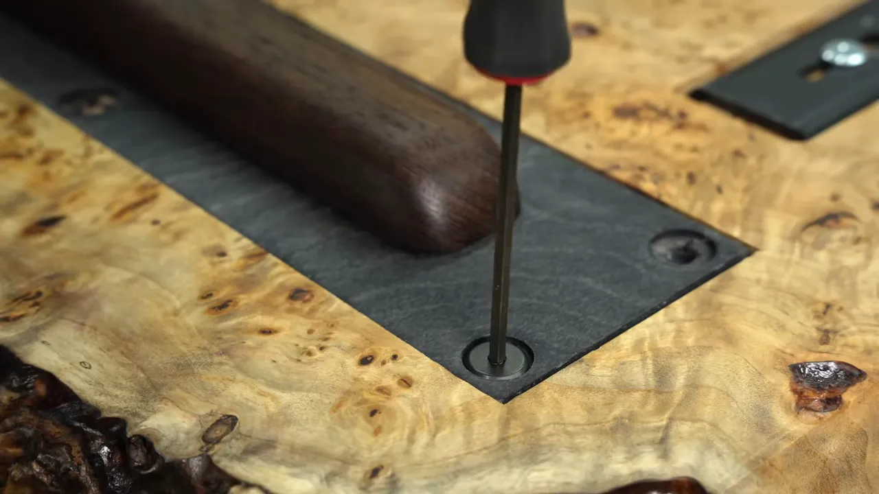 A curved dark wood leg attached to a black rectangular plate recessed into the burl underside