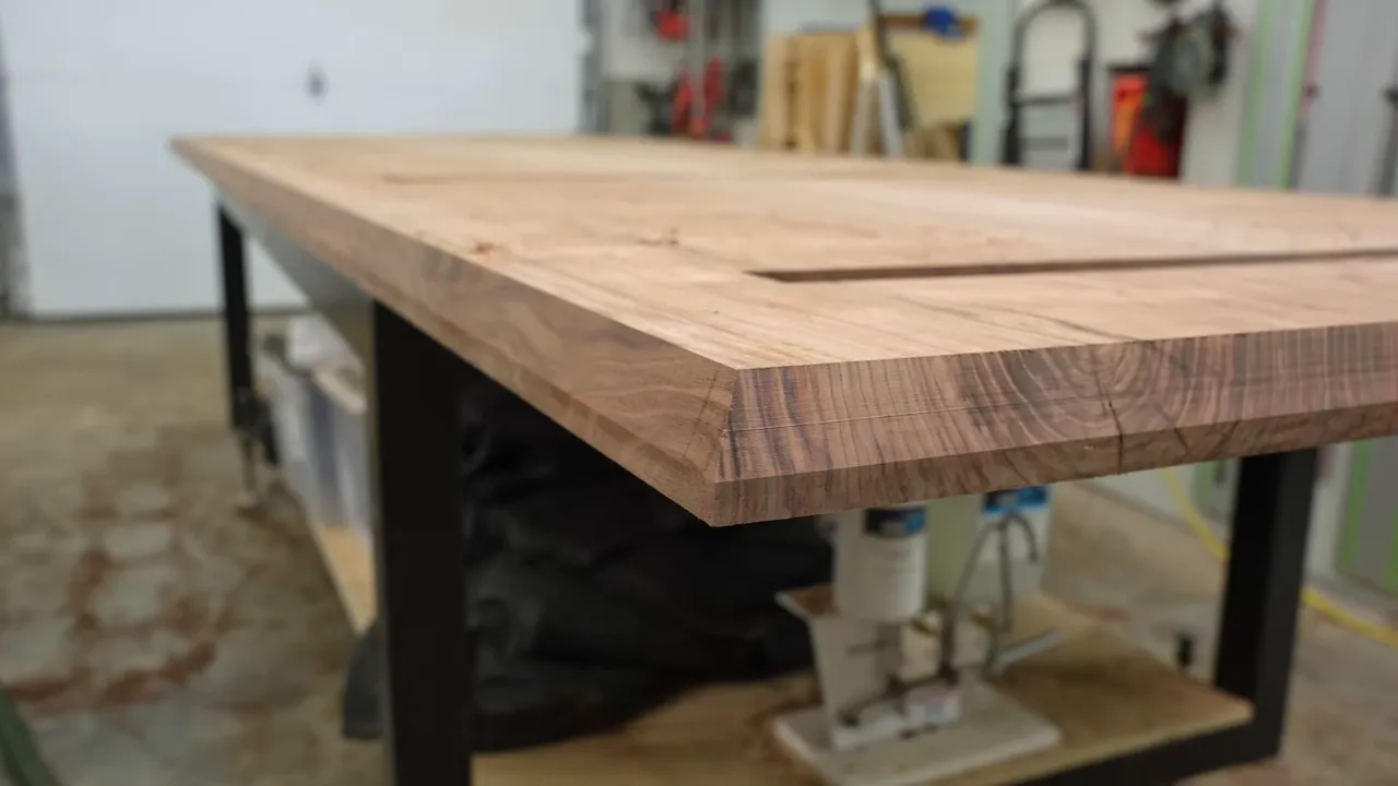 Close side view of the walnut tabletop showing a deep angled chamfer beneath the edge