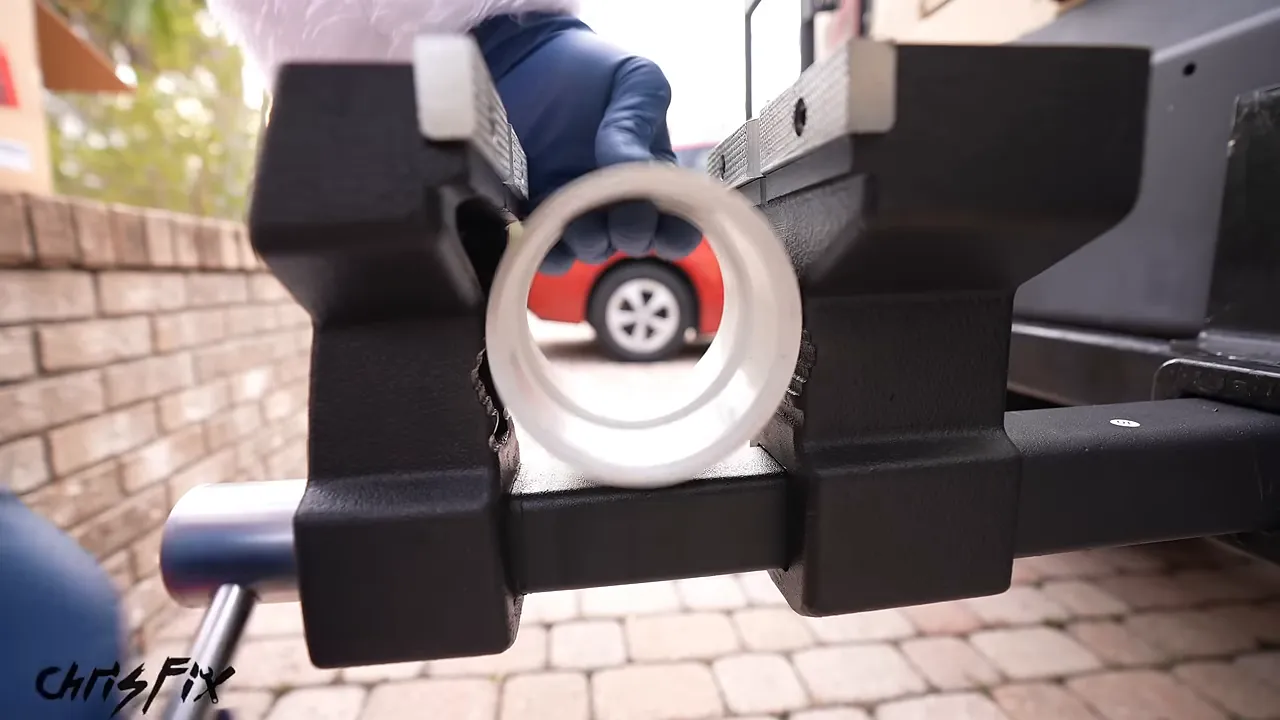 Hitch-mounted vise gripping a short round pipe in its lower jaws