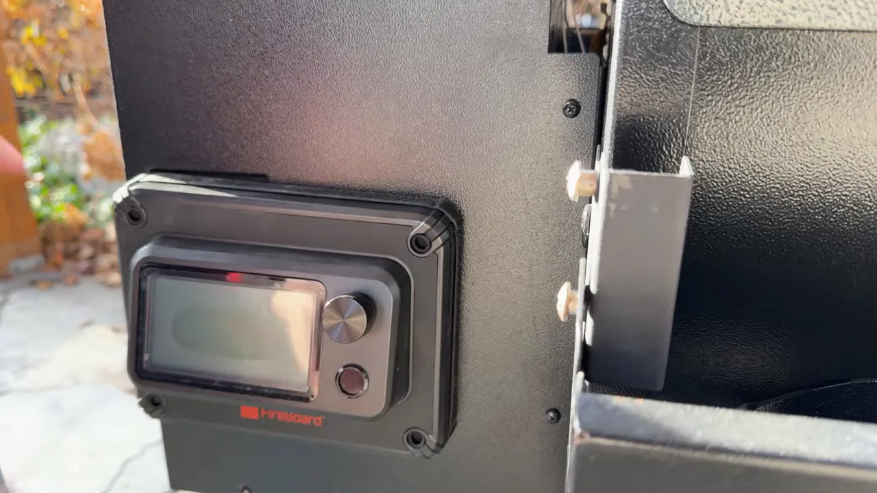 FireBoard controller mounted on the Traeger hopper housing beside the cooking chamber