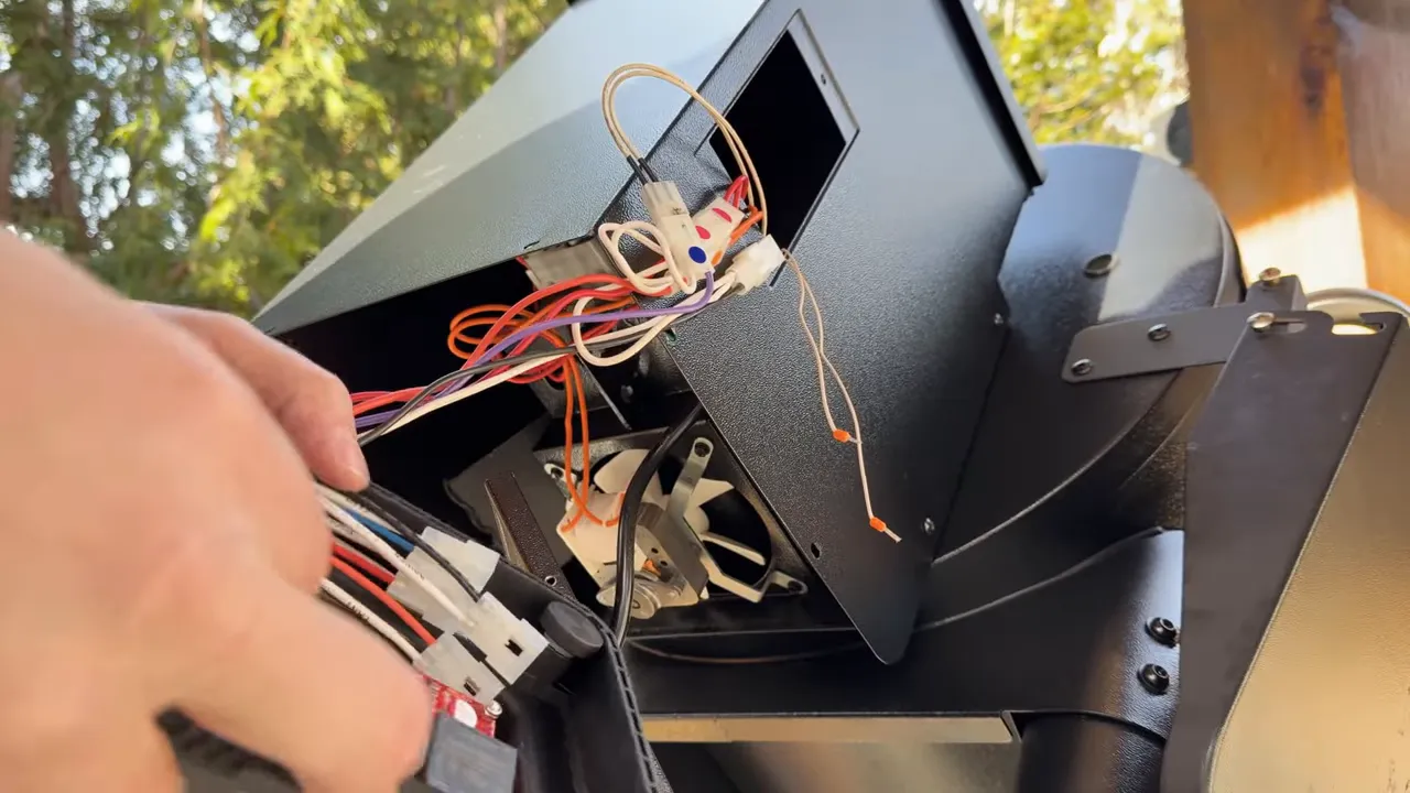 Close-up of the replacement controller wiring and white connectors beside the open hopper housing
