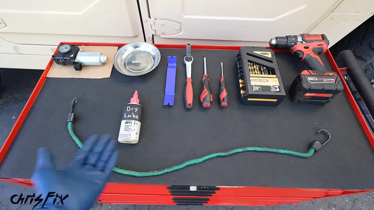 Window motor, parts tray, trim tool, hand tools, drill bits, drill, lubricant, and bungee cord on a tool cart