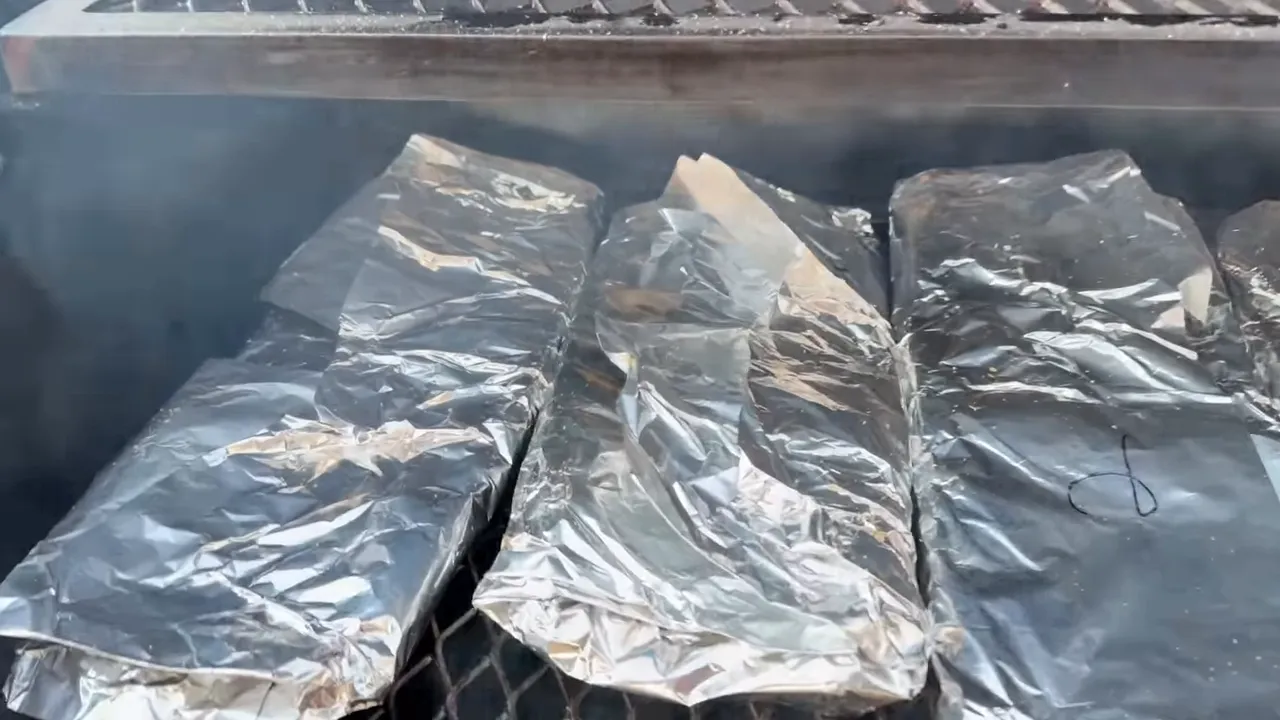 Four foil-wrapped rib packages arranged on the El Fuego Trio cooking grate