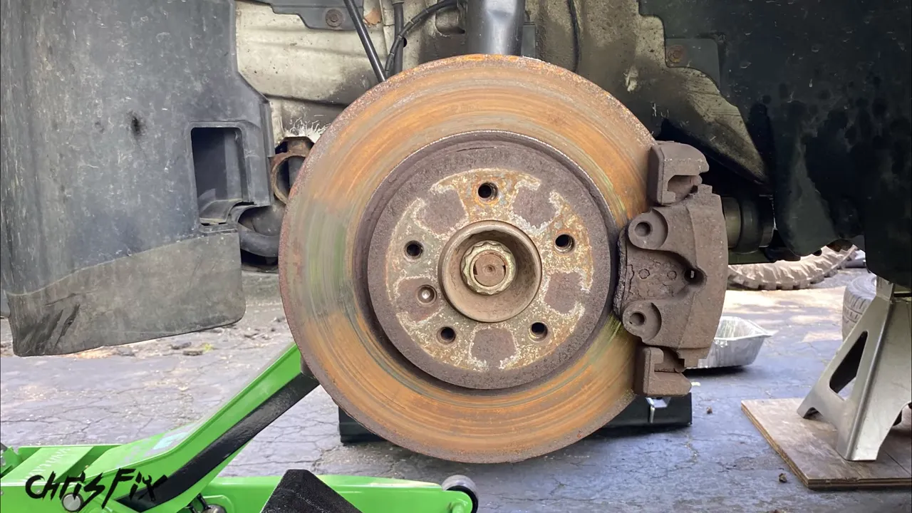New silver brake rotor and caliper installed on the BMW with the wheel removed