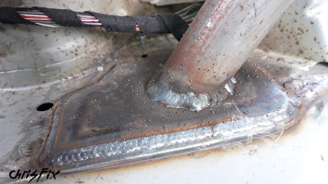 Roll cage tube welded to a broad steel mounting plate on the BMW floor