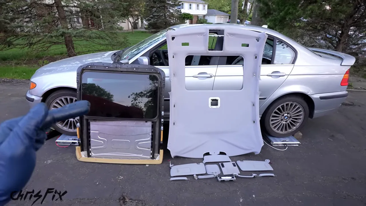 Removed sunroof assembly, headliner, visors, and roof accessories arranged beside the BMW