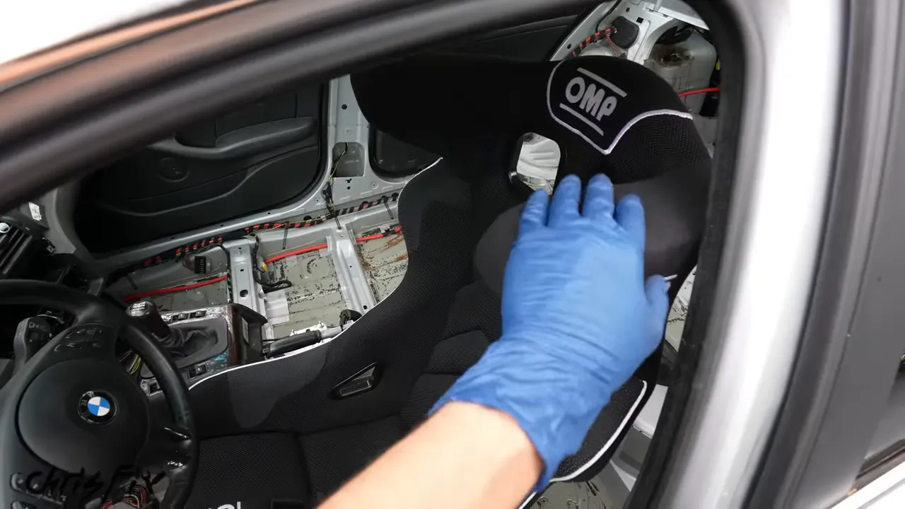 BMW interior with a black racing seat, exposed metal floor, and stripped center console area