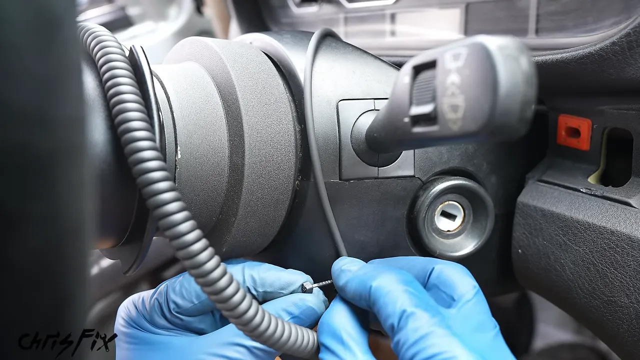 Coiled steering wheel button cable secured beneath the steering column trim