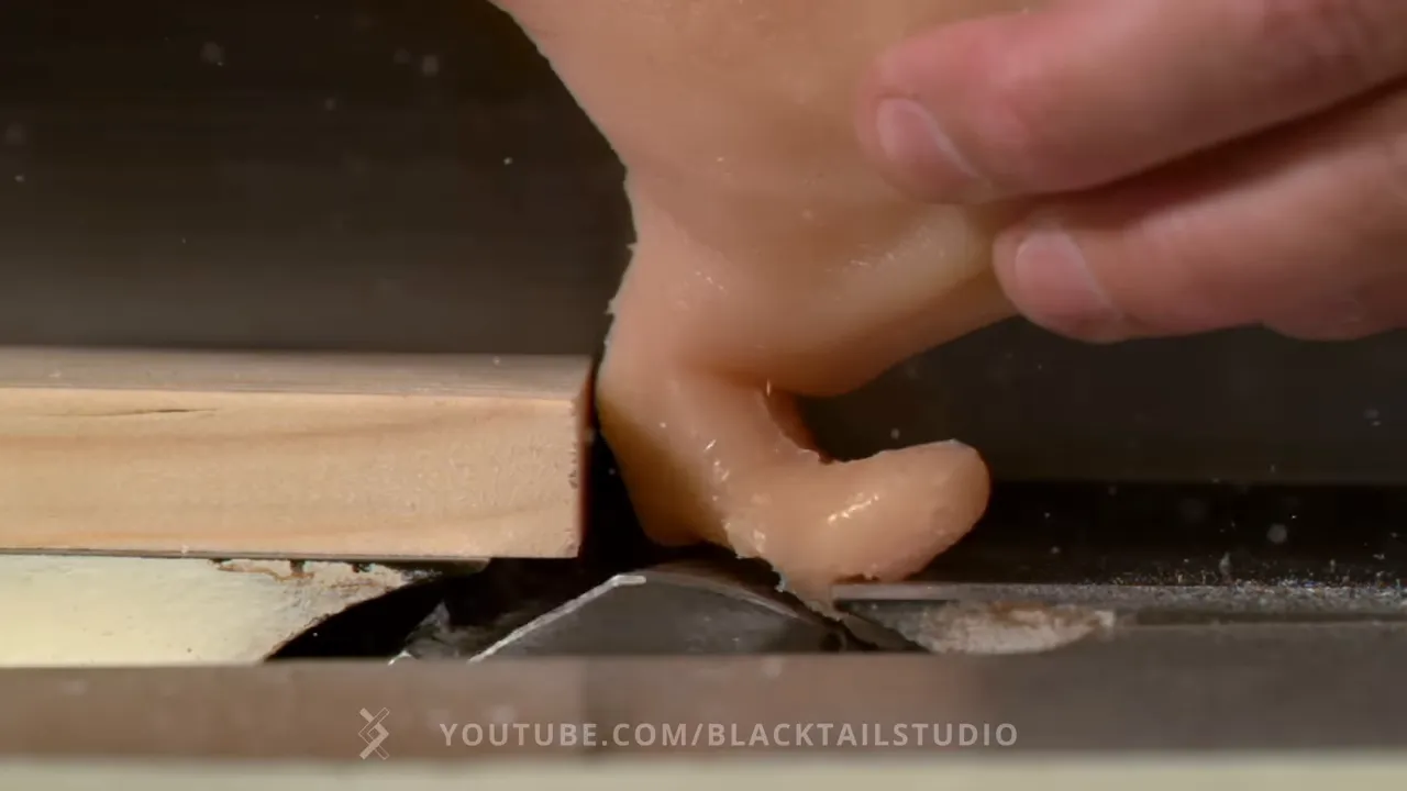 Artificial thumb folded backward at the jointer cutter opening beside a wood board