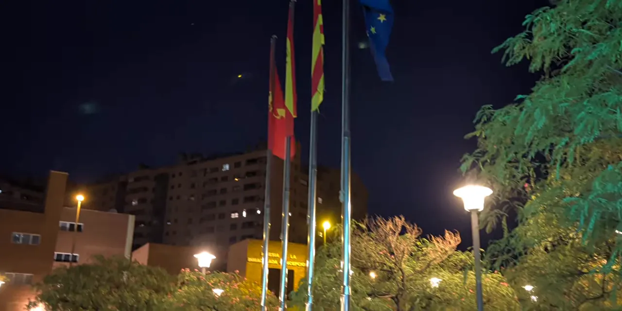 Night scene with illuminated flagpoles, streetlights, and small light reflections in the dark sky