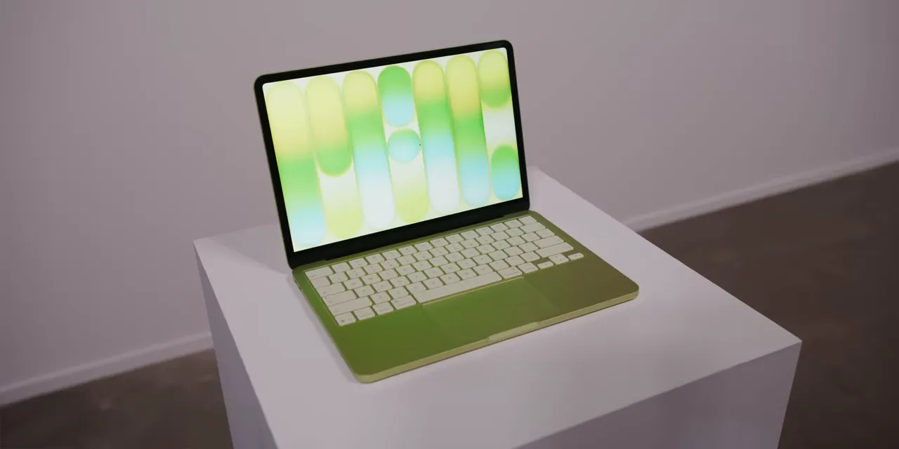 Citrus MacBook Neo open on a white display pedestal