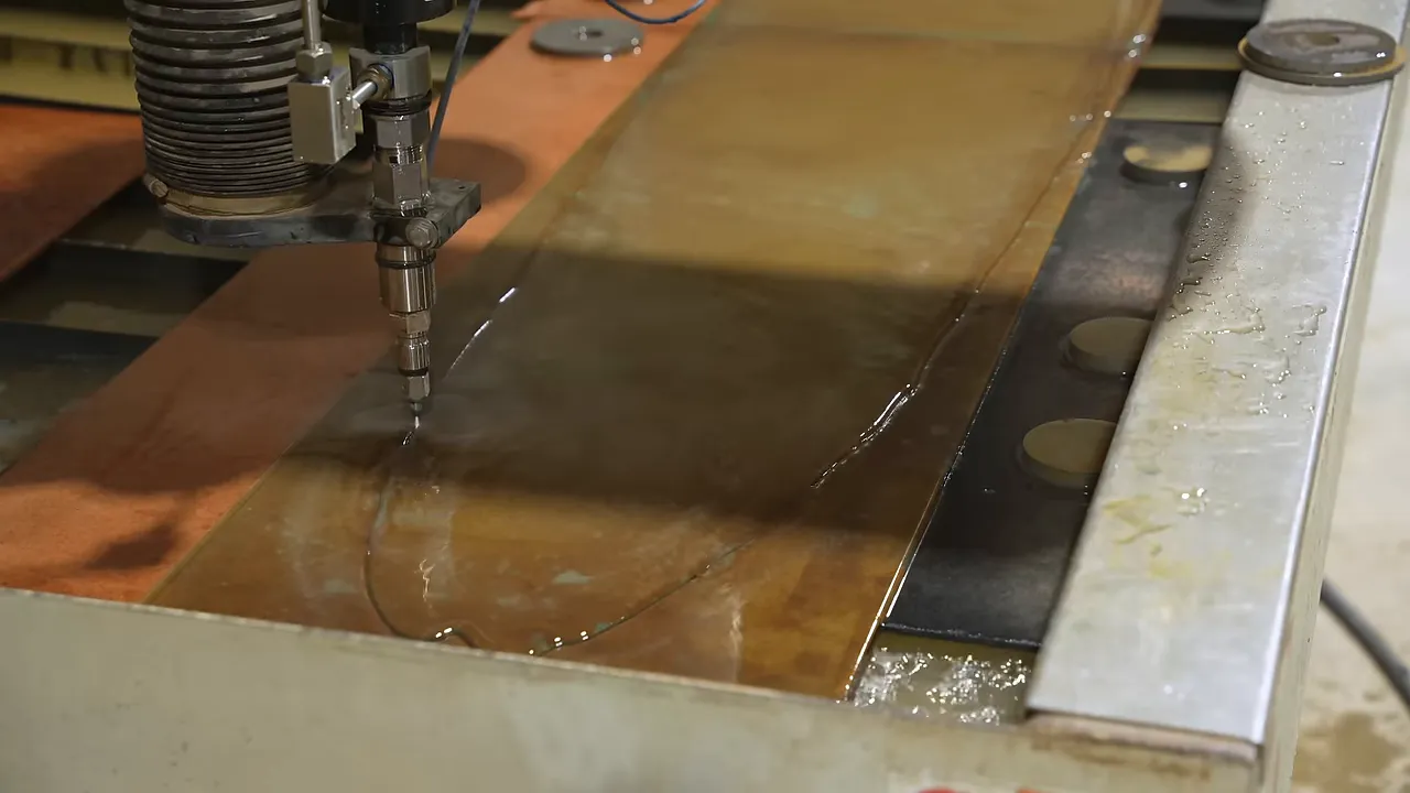 Waterjet nozzle cutting an irregular outline in a sheet of glass