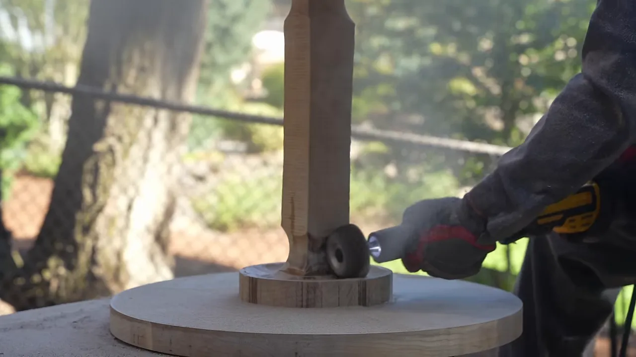 A carving tool shaping the flared connection between a maple stem and circular base