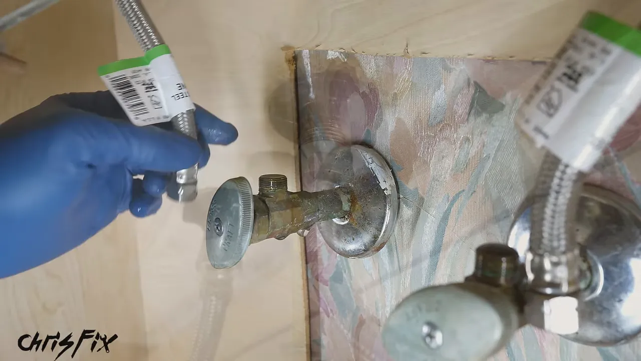 Underside of the sink showing two faucet mounting nuts, supply hoses, and a lift rod