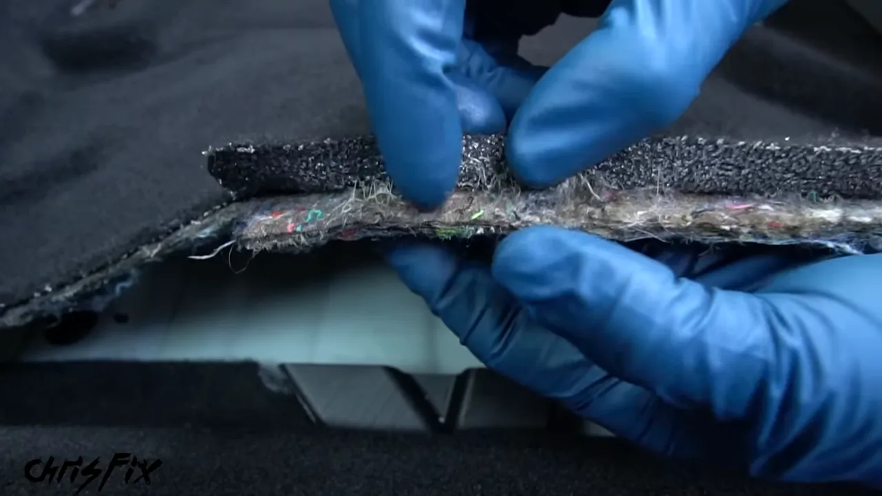 Gloved hands holding up an edge of carpet to show the thick backing underneath