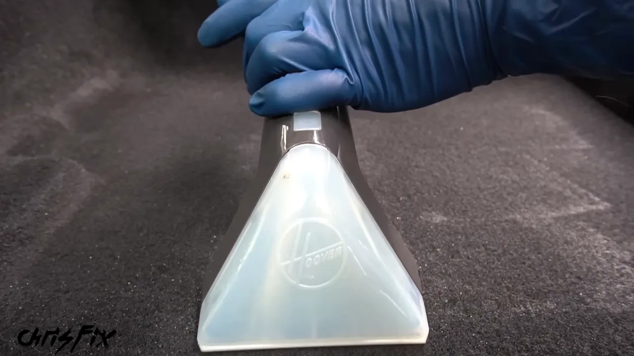 Transparent extractor nozzle being pulled across dark car carpet