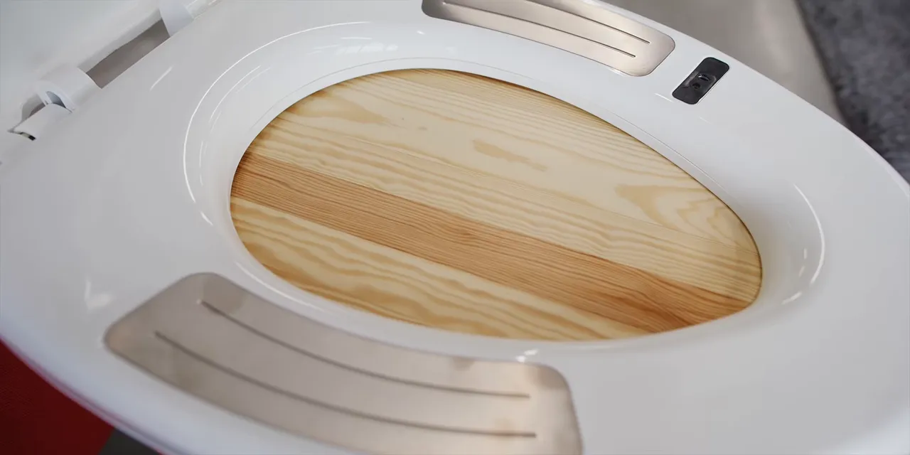 White toilet seat with several metal contact panels around the seating surface