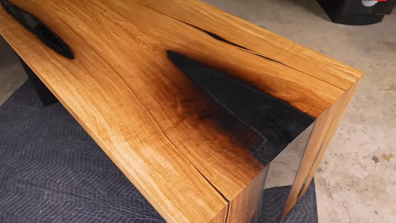 Finished oak desktop with glossy black charred areas wrapping over the waterfall corner