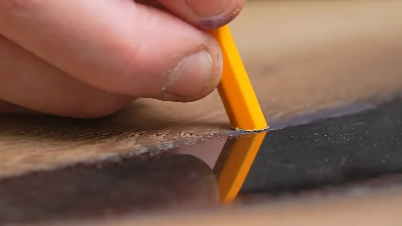 Tiny sandpaper tip on a yellow pencil working along the glossy epoxy and oak boundary