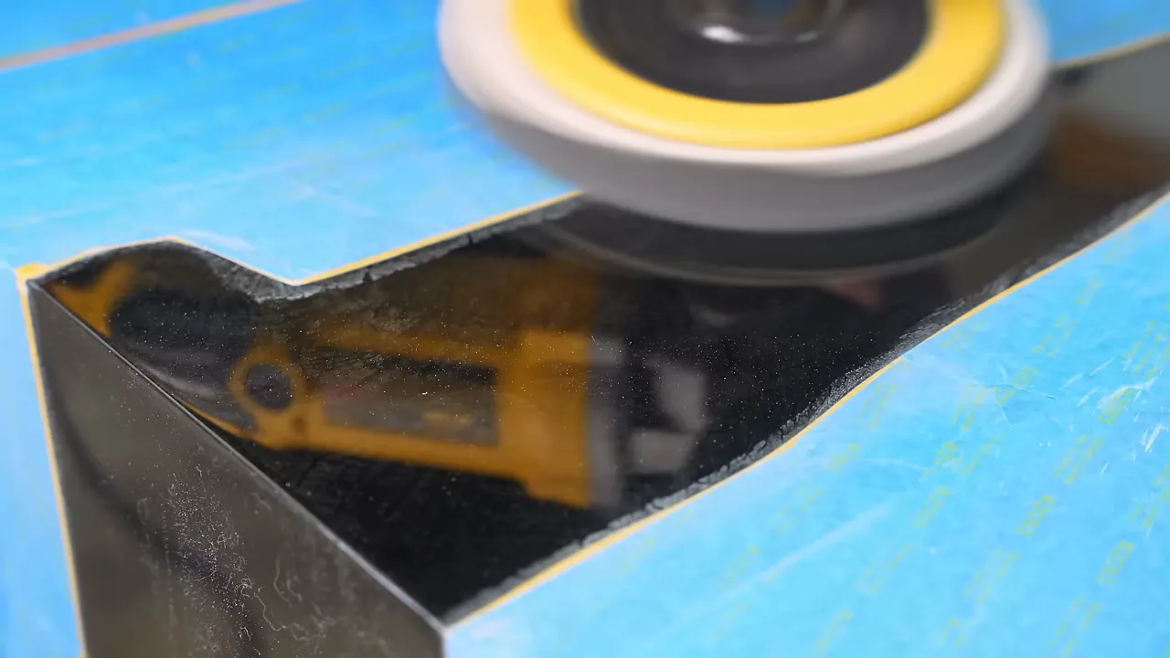 Polishing pad on glossy black epoxy surrounded by blue masking tape