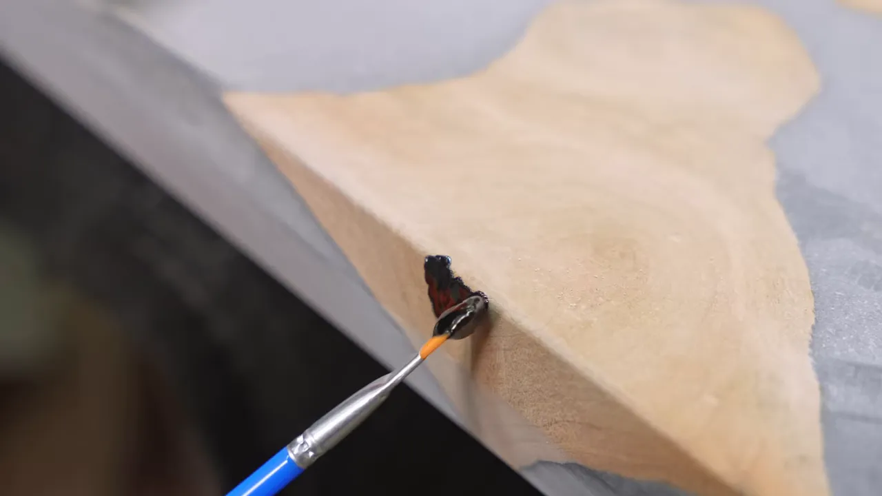 Black epoxy patch being applied to a defect on the vertical edge of a tabletop