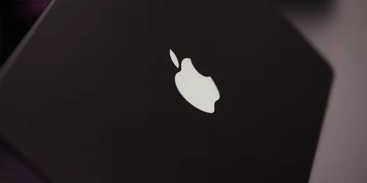 Illuminated white Apple logo on the dark lid of a MacBook Pro