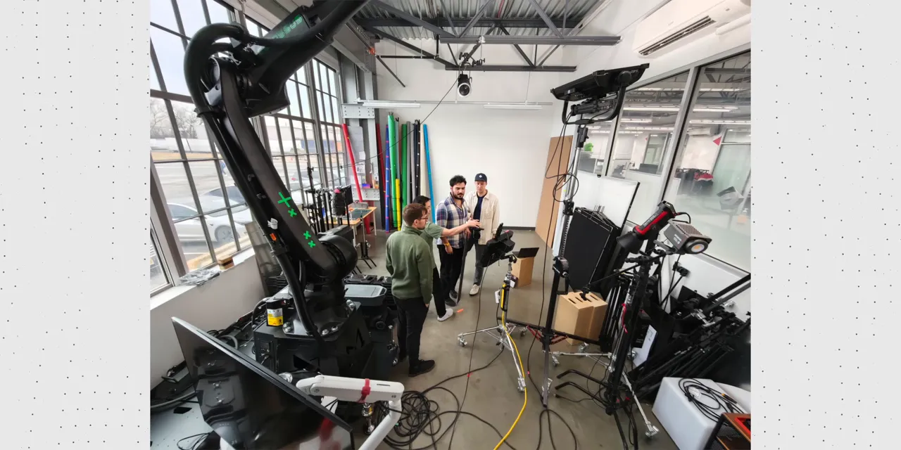 Ultrawide photograph of a studio with windows, lighting equipment, cables, and people