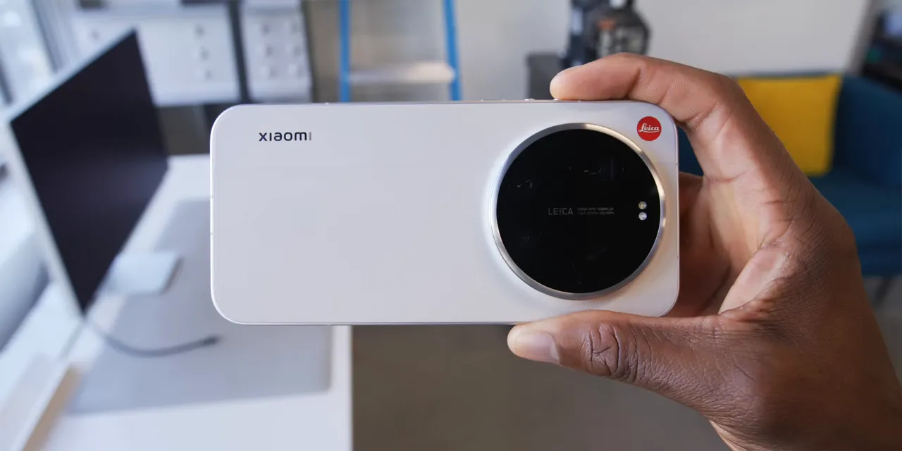Cream Xiaomi phone held horizontally with a large circular camera module and red Leica logo