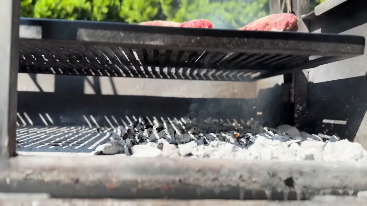 Beef rib racks on a raised grill grate above a bed of wood coals