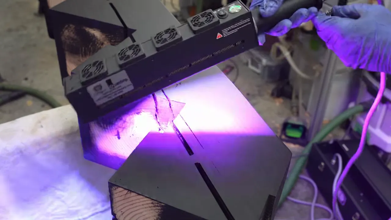 A purple curing light passing over the black notched timber stringer