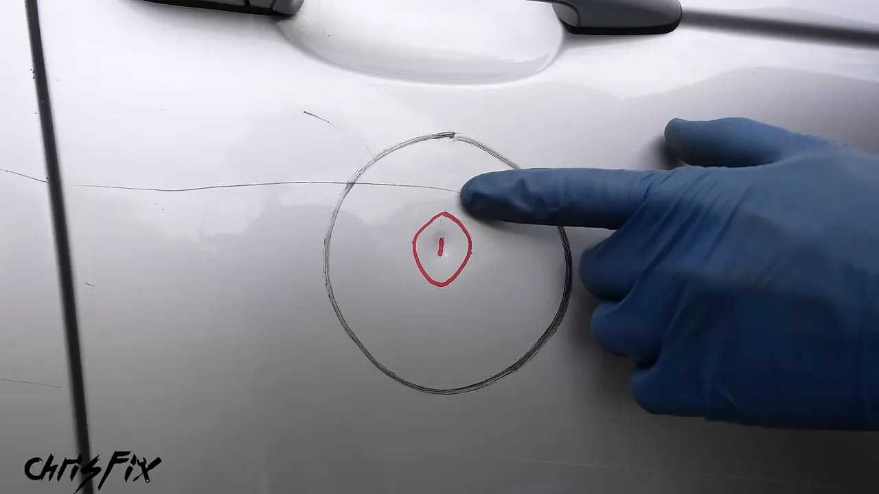 Small central dent and a wider surrounding area outlined on a silver door